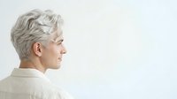 Senior woman with short gray hair in profile view wearing beige shirt against white background, suitable for healthcare, wellness, and aging-related design projects.