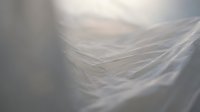Close-up macro of white blonde hair strands with soft natural lighting creating ethereal movement and texture for beauty and haircare concepts.
