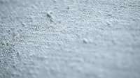 Close-up macro view of water droplets on gray fabric textile surface showing detailed fiber weave structure and moisture beads for backgrounds.