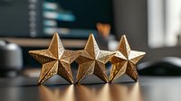 Three golden decorative stars arranged in row on reflective surface against blurred office background, symbolizing excellence, achievement and quality rating.