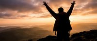 Male hiker with backpack celebrating success on mountain peak at golden sunset with arms raised, achievement and freedom concept in nature landscape.