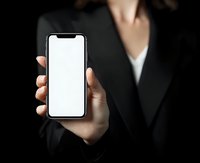 Businesswoman in formal suit holding smartphone with blank white screen against dark background, perfect for app or website mockup.