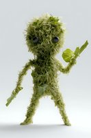 Playful character made from fresh green lettuce leaves and black olives for eyes standing on white background, creative food art composition for healthy eating concept.