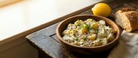 Creamy hummus with chickpeas, tahini, and garlic served in a wooden bowl with fresh lemon and toasted bread for dipping and appetizers.