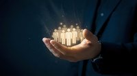 Businessman in dark suit holding glowing human figures in palm, representing team management, leadership, and workforce development for corporate growth and organizational success.
