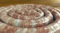 Raw sausage coils arranged in spiral pattern, uncooked meat product ready for cooking or grilling, fresh butcher shop ingredient.