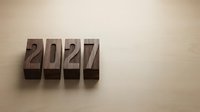 Wooden letterpress blocks spelling 2027 on a light wooden surface, copy space for new year greeting cards and business calendars.