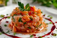 Fresh salmon tartare garnished with parsley and chives on white plate, decorated with red wine reduction sauce in circular pattern, close up macro food photography.