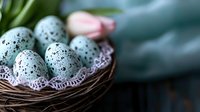 Speckled blue quail eggs in rustic nest with delicate lace doily and soft pink flower against dark wooden background, creating nostalgic spring atmosphere.