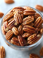 Fresh roasted pecan nuts in glass bowl, macro close up view showing detailed texture and natural brown color, healthy organic snack for cooking and eating.