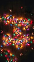 Merry and Bright text formed by colorful glowing Christmas lights on rustic wooden background with festive ornaments and pine branches.