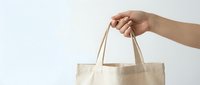 Hand holding eco-friendly cotton tote bag on white background. Sustainable shopping concept for zero waste lifestyle and environmental awareness campaigns.