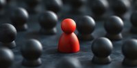 Red figure standing out among black figures on dark surface, representing uniqueness, leadership, and individuality in business concept. Different thinking concept.