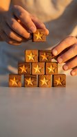 Hands arranging wooden blocks with golden stars in pyramid formation representing customer rating, quality excellence and business success evaluation.