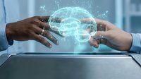 Two hands reaching toward glowing digital brain hologram with neural network connections, representing artificial intelligence collaboration and technology partnership.