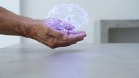 Elderly hand holding glowing purple brain hologram representing mental health, memory care, neurology, and cognitive wellness in healthcare setting.