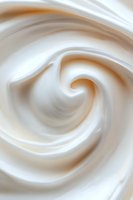 Smooth swirling cream texture in white and beige tones creates abstract spiral pattern, suitable for food industry backgrounds and cosmetic packaging designs.