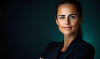 Confident Caucasian businesswoman in dark blazer against turquoise background, arms crossed, professional headshot with dramatic lighting and soft smile.