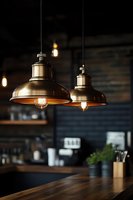 Industrial copper pendant lights hanging over wooden counter in modern kitchen interior with warm Edison bulb illumination for home design.