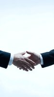Business handshake between two professionals in dark suits on white background symbolizing partnership, agreement, and successful deal completion.