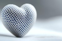 White heart with blue polka dot pattern on soft textile background, romantic minimal composition in pastel tones. Modern love concept for greeting cards and valentines.