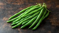 Fresh green string beans on dark rustic background, macro food photography with selective focus and natural lighting for cooking blogs and recipes.