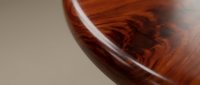 Close-up of polished wooden bowl surface showing rich grain patterns and glossy finish, suitable for home decor, furniture design, and craftsmanship content.