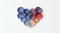 Colorful paper circles arranged in heart shape on white background, creating dimensional effect for greeting cards and love-themed designs.
