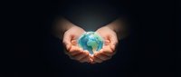 Young adult hands cradling glowing globe against dark background, symbolizing environmental protection, sustainability, and global responsibility for business and eco-conscious design.