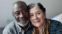 Loving senior couple embracing and smiling at camera, showcasing genuine connection and happiness in retirement years.
