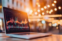 Laptop displaying financial trading charts and market analysis graphs with blurred bokeh lights background creating atmospheric business environment.