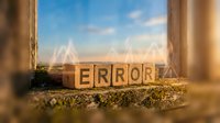 Wooden blocks spelling error displayed on weathered windowsill with golden sunlight and blue sky backdrop, suitable for web design, business presentations, and educational materials.