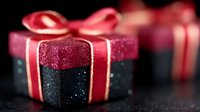 Festive black and pink glitter gift box with red ribbon bow on dark background, selective focus with bokeh effect creates magical holiday atmosphere.
