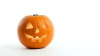 Carved orange pumpkin jack-o-lantern with glowing triangular eyes and smiling mouth on white background isolated for Halloween decorations and designs.