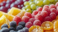 Fresh colorful fruit platter with raspberries, blackberries, grapes and orange slices arranged in rows, macro food photography with selective focus.