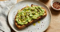 Avocado toast on artisan bread with crushed red pepper flakes and black pepper on ceramic plate. Healthy breakfast or brunch meal for social media content.