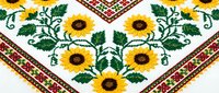 Traditional Ukrainian embroidery pattern with sunflowers and geometric border on white fabric. Folk art textile design for cultural projects and crafts.
