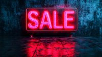 Glowing neon sale sign on dark textured wall with red reflection on wet floor surface creates dramatic retail atmosphere for promotional marketing and advertising.