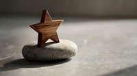 Wooden star decoration placed on smooth stone creating minimalist zen composition for meditation and mindfulness practices in natural lighting.