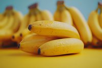 Fresh ripe yellow bananas on vibrant yellow background with teal wall, macro food photography with selective focus and soft natural lighting.