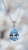 Elegant silver necklace with teardrop blue gemstone pendant and diamond accents on chain, luxury jewelry accessory for special occasions.