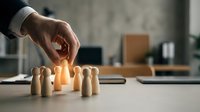 Business hand selecting glowing wooden figure from group representing talent acquisition, leadership choice, and human resources management in office.