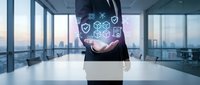 Businessman holding laptop displaying digital security icons and network symbols in modern office with city skyline view for cybersecurity and technology concepts.