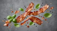 Crispy bacon strips with fresh basil leaves and black peppercorns scattered on gray surface, perfect for culinary designs and food advertising projects.