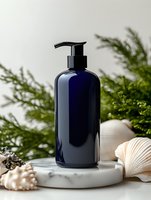 Navy blue glass pump bottle on marble stand with seashells and green plants, cosmetic packaging mockup for skincare, bathroom products or aromatherapy.