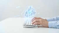 Professional businessman hands typing on white keyboard with floating cloud computing icons and data transfer symbols for digital transformation concepts.