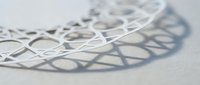 White geometric lattice structure with intricate curved patterns casting soft shadows on clean surface for modern design and architectural concepts.
