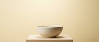 Minimalist ceramic bowl on wooden block against neutral beige background for modern home decor and kitchen styling concepts.