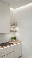 Modern minimalist kitchen interior with white cabinets, wooden countertop, built-in shelving and LED strip lighting for contemporary home design.