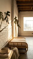 Minimalist rattan daybed in a sunlit loft with white brick walls, concrete floor, and tropical plant shadows for boho interior design.
